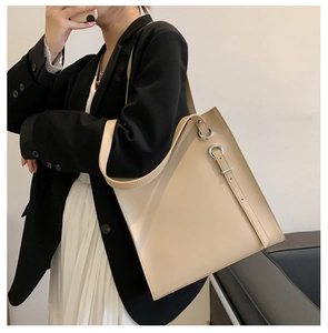 Beige leather tote bag with silver eyelets shown on shoulder for professional commute