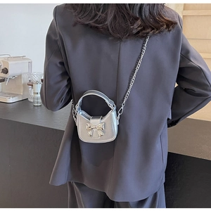 Silver metallic mini crossbody bag with a 3D bow and chain strap shown on a model