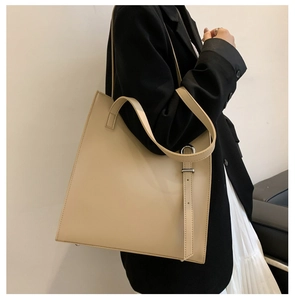 Side view of a beige minimalist faux leather tote bag worn on shoulder for commuting