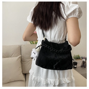 Détail d'un sac à bandoulière noir plissé avec un charmant monstre en peluche blanc