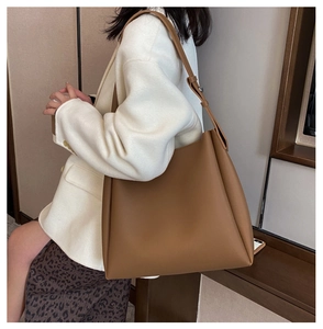 Brown leather tote bag worn by model, showing spacious interior and adjustable shoulder strap