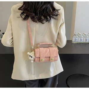 Detail of pink cylindrical crossbody bag with pleated texture and white plush pendant charm