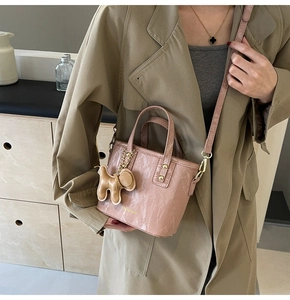Sac à main rose marbré avec pendentif chien et bandoulière porté sur un trench-coat