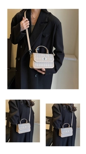 Detail view of beige quilted crossbody bag with silver twist lock and slim shoulder strap