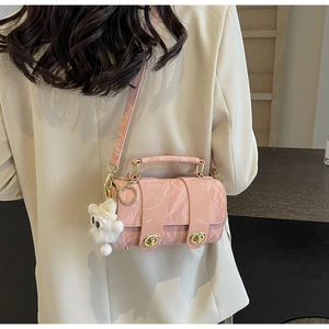 Pink cylinder shoulder bag with glossy pleated texture and a cute plush doll charm