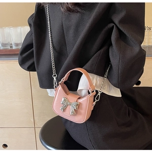 Detail of pink half-moon bag with large silver metal bow buckle and chain strap