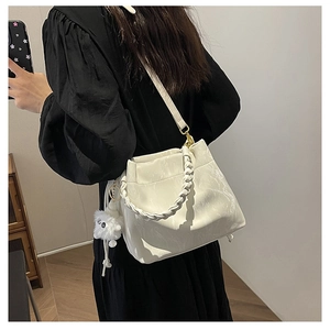 Détail du sac seau à texture marbrée avec poignée tressée et pompon sur un mannequin