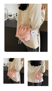 Pink bucket bag with a thick woven handle and a cute plush monster charm detail