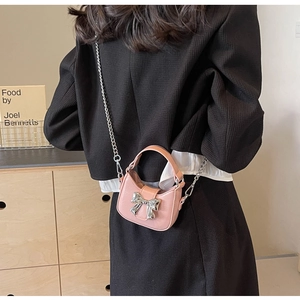 Rear view of a model wearing a pink mini crescent bag with silver bow and chain strap