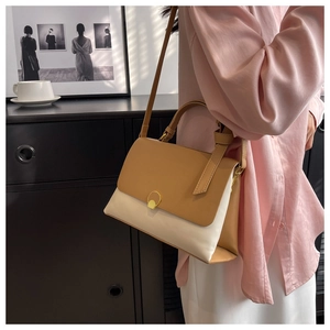 Detail of a chic contrast color leather handbag with a round golden magnetic lock buckle