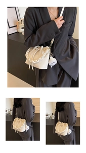 Detail of cream white bucket bag featuring woven handle and plush charm accessory