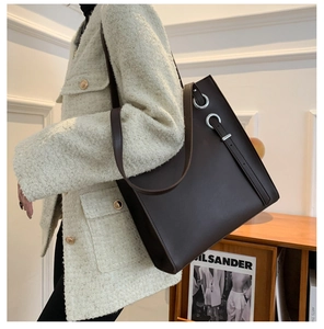 Detailed side view of the dark brown leather tote bag with silver eyelet accents