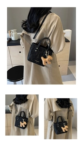 Détail du sac seau noir texturé avec ferrures dorées et accessoire breloque chiot marron