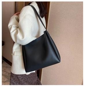 Side view of large black matte leather tote bag on model showing spacious interior capacity
