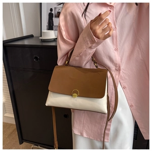 Close-up of contrast color handbag featuring caramel flap and gold ring buckle detail