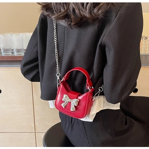 Detailed back view of a mini red leather bag with a large silver bow and chain strap