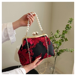 Detailed shot of black vintage clutch with red 3D floral embroidery and pearl handle