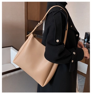 Close-up of beige matte leather tote bag worn with black coat for a stylish contrast