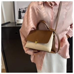 Detail of color-block leather handbag with gold buckle held by model in silk shirt