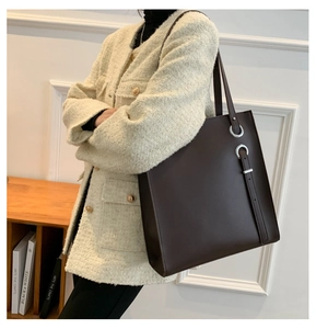 Detailed side view of dark brown leather tote bag with silver ring hardware accents