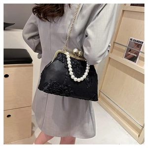 Detail of black lace embroidery handbag with pearl handle and gold chain strap
