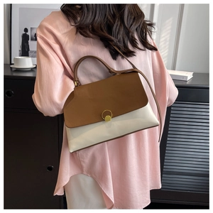 Detail view of two-tone contrast shoulder bag with gold ring buckle and leather strap
