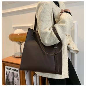 Detail view of large dark brown leather tote bag with adjustable strap in minimalist style