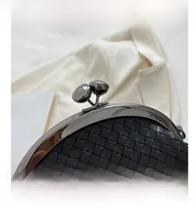 Detail of black woven shell bag featuring a dark gunmetal round lock and textured finish