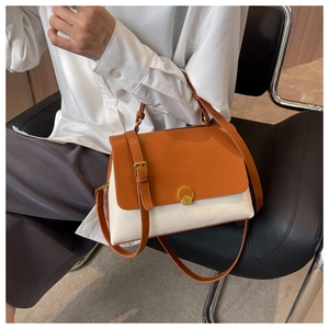 Detail of contrast orange and cream flap bag with gold round twist lock hardware