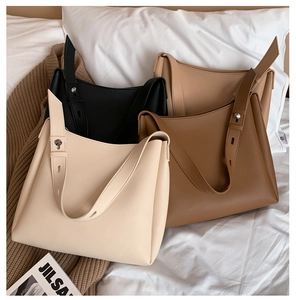 Detail of minimalist leather tote bags in various colors on a soft bed background