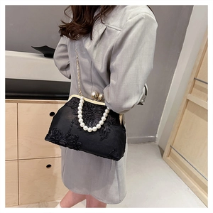 Detail of black lace embroidery handbag featuring elegant pearl handle and gold chain