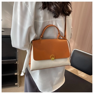 Close-up of contrast color shoulder bag with gold metal buckle on a female model