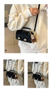 Detail of glossy pleated leather cylinder bag with gold locks and cute monster charm