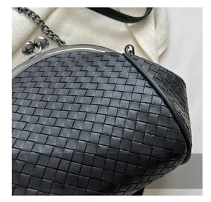 Detailed close-up of a black leather woven crossbody bag with vintage metal frame clasp