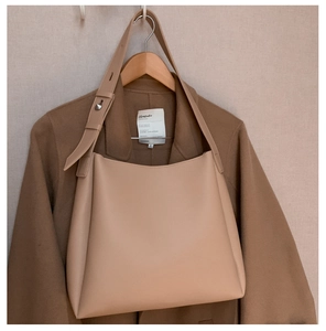 Detail of adjustable wide shoulder strap and metal buckle on beige soft leather tote bag