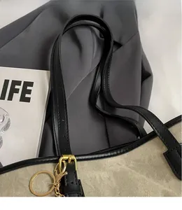 Detail of canvas tote bag with black leather handles and gold metal adjustment buckles