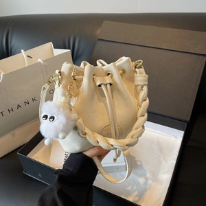 Fashionable cream bucket bag with braided handle and cute fur ball charm for women