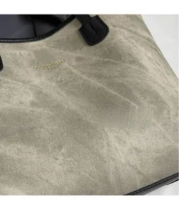 Close-up of grey frosted fabric texture with golden fashion logo on a tote bag