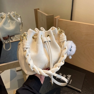 Cream drawstring bucket bag with woven handle and plush charm, versatile crossbody style