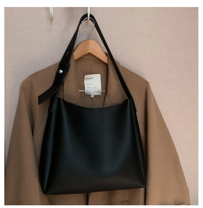 Close-up of black minimalist tote with adjustable wide strap and silver metal buckle