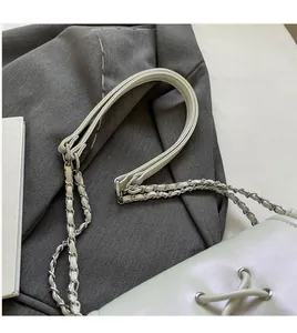 Dettaglio della tracolla a catena con pelle intrecciata e maglie metalliche della borsa beige
