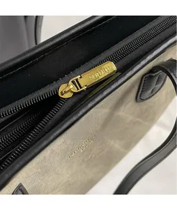 Detailed close-up of golden hardware zipper and sage green matte fabric on tote bag