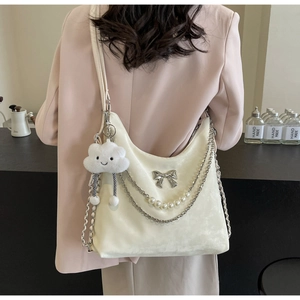 Détail du sac hobo en velours crème avec chaîne en perles et nœud argenté chic