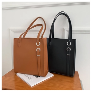 Detail view of brown and black leather tote bags with silver metal ring buckle accents