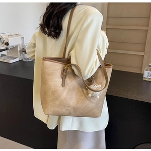 Detail of vintage textured khaki tote bag with plush charm in a cozy cafe setting