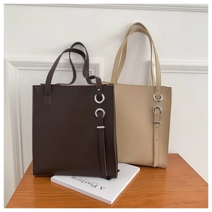 Detailed view of beige and dark brown leather tote bags with elegant metal ring buckle