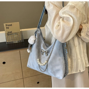 Détail d'un sac cabas en faux suède bleu clair avec nœud argenté et chaîne de perles
