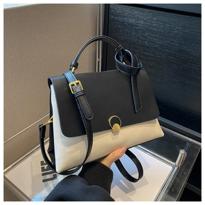 Detail of contrast color handbag with gold circular buckle and adjustable shoulder strap