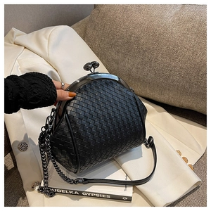 Detail of black woven shell bag with vintage metal clasp and elegant chain strap