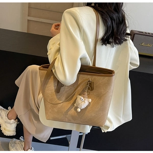 Large khaki tote bag shown on model with a cute plush charm for daily commuting style